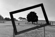 Tilted empty frame overlooking people walking across a grassy field
