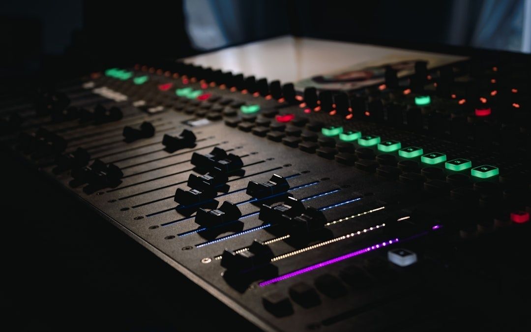 Illuminated audio mixing console with sliders, knobs, and colored controls