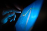 Hand interacting with a blue screen showing an abstract line graphic