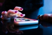 Hand hovering over a smartphone touchscreen, poised to tap