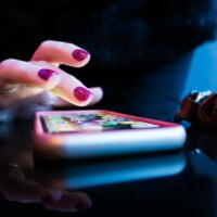 Hand hovering over a smartphone touchscreen, poised to tap